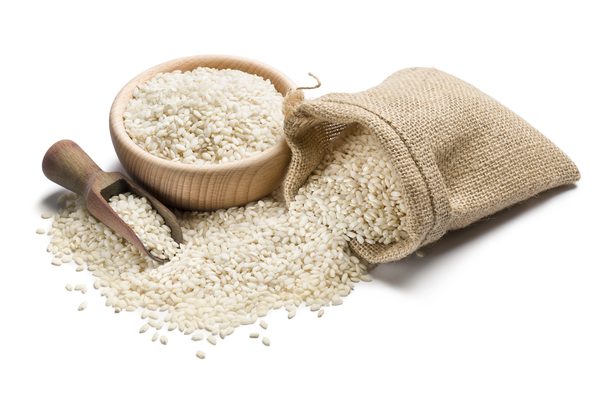 white rice in wooden bowl and juta bag on white background